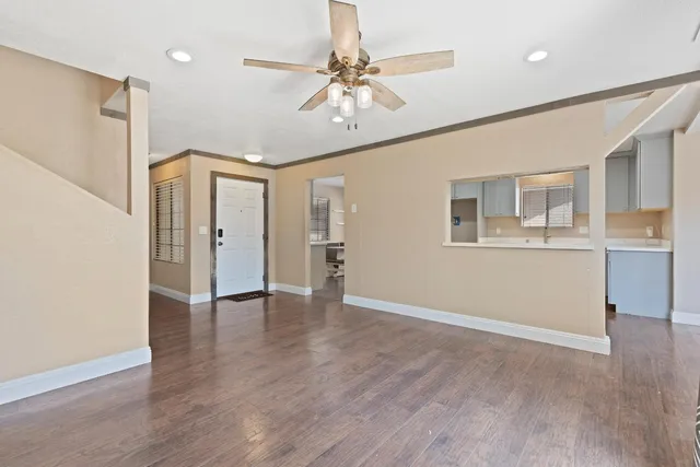 a view of an empty room with window and wooden floor
