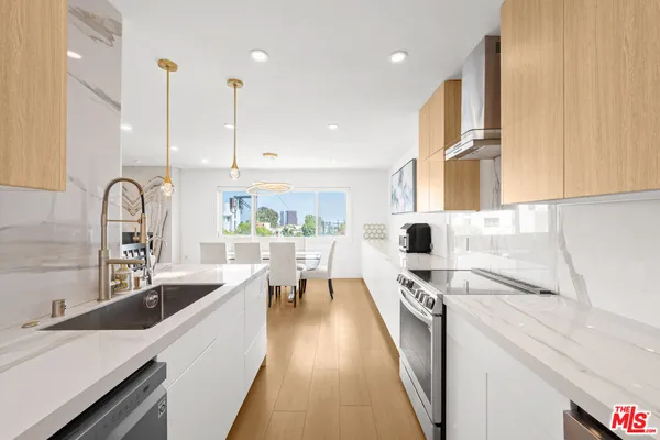 a kitchen with stainless steel appliances a sink a stove top oven a counter space and cabinets