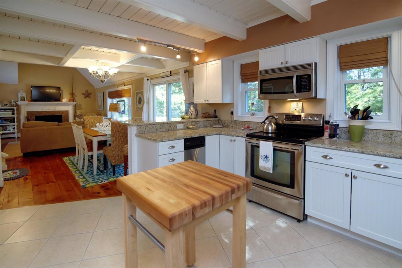 71 Captain Carltons Road Cotuit, MA 02635 - Photo 6 of 21 a kitchen with stainless steel appliances granite countertop a stove top oven a sink dishwasher a dining table and chairs with wooden floor