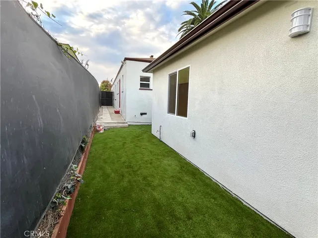 a backyard of a white house with potted plants