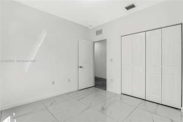 a view of kitchen with refrigerator and white cabinets