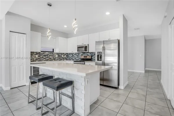 a kitchen with white cabinets and refrigerator