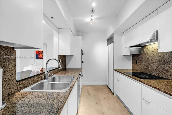 a kitchen with kitchen island stainless steel appliances granite countertop a sink and refrigerator