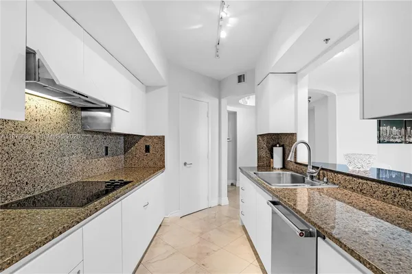 a large kitchen with granite countertop a sink and cabinets