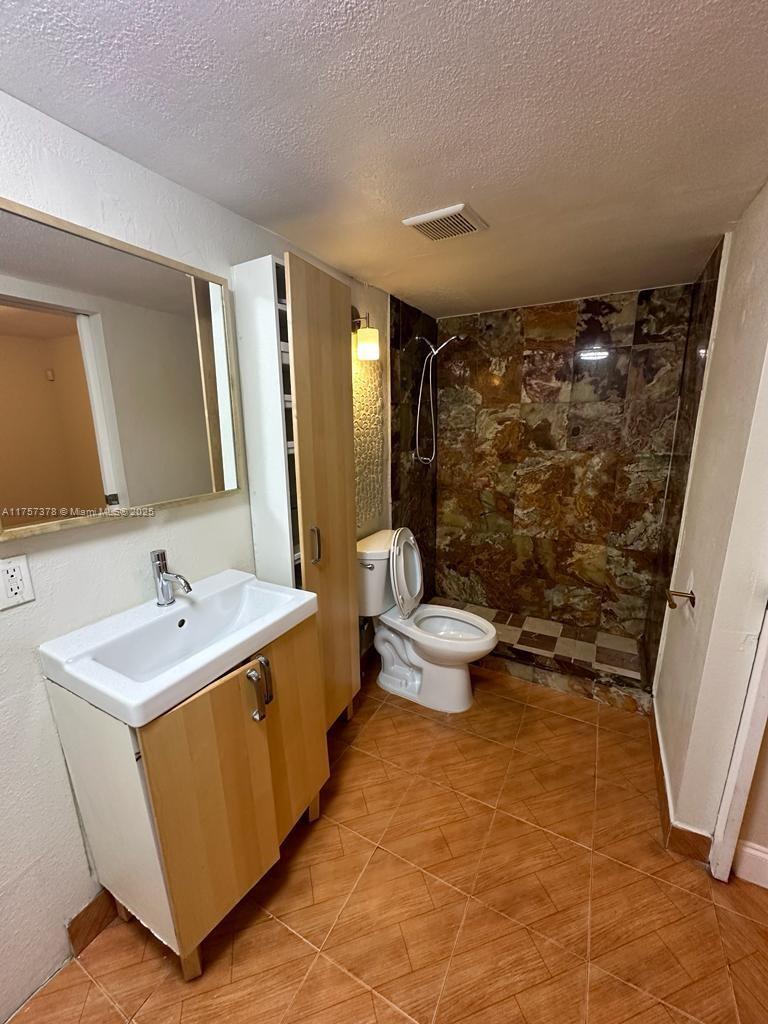 492 Northwest 165th Street, Unit C211 Miami, FL 33169 - Photo 23 of 26 a bathroom with a double vanity sink toilet and shower