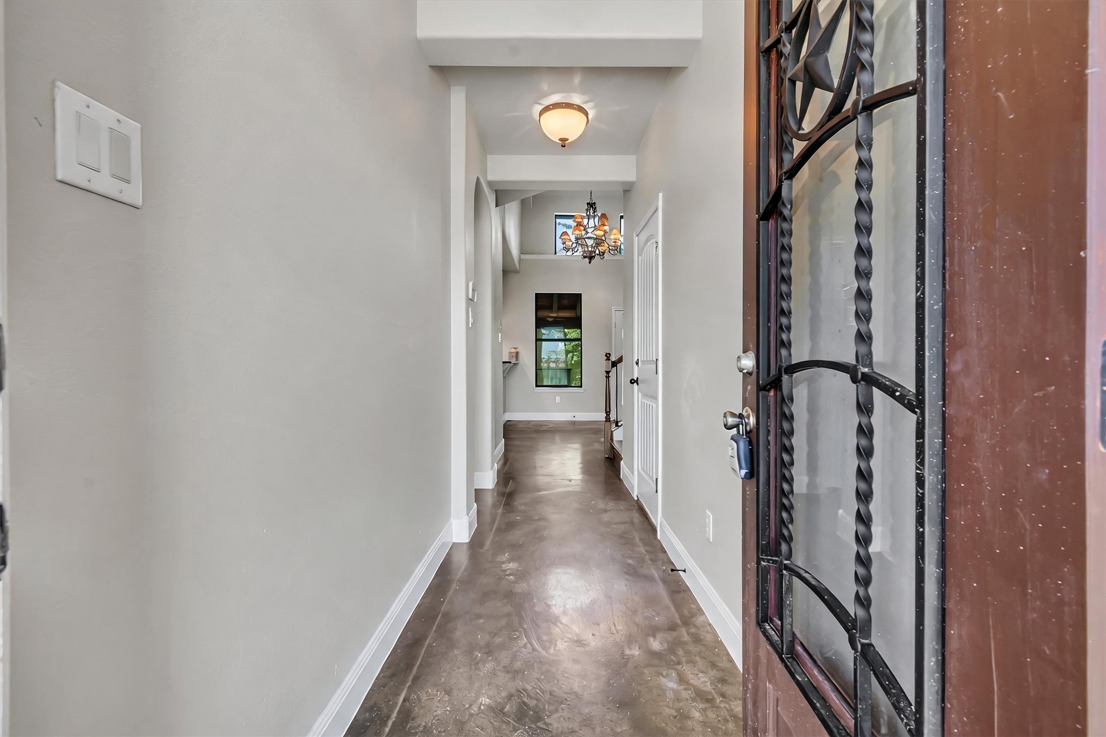 1010 Immanuel Road, Unit 103 Pflugerville, TX 78660 - Photo 4 of 30 A welcoming entryway boasts a wrought-iron detailed front door and smooth concrete flooring, extending into the home's interior.