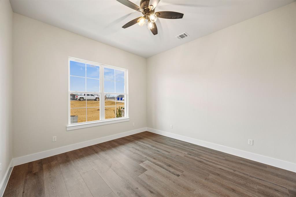 13835 Cashs Mill Road Sanger, TX 76266 - Photo 9 of 32 an empty room with wooden floor fan and windows
