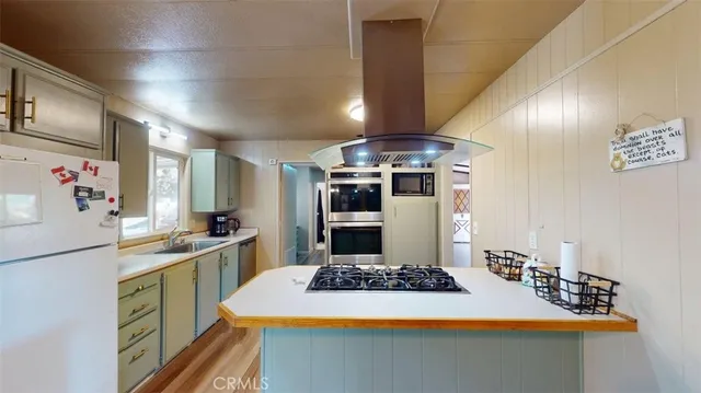 a kitchen with stainless steel appliances a stove a sink dishwasher and a refrigerator with wooden floor