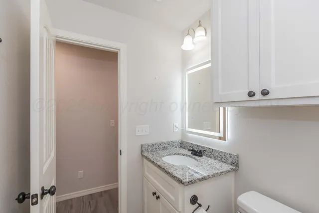 a view of an empty room with wooden floor and a ceiling fan