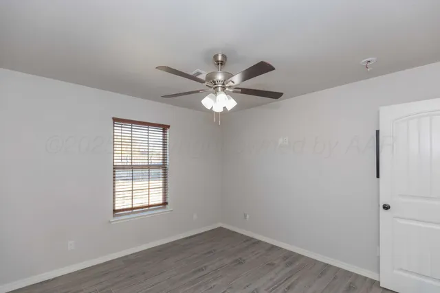 an empty room with wooden floor and ceiling fan