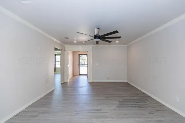 a view of an empty room with a window and wooden floor