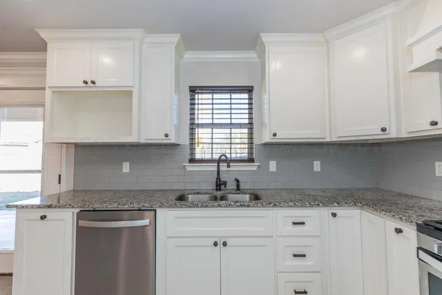 a kitchen with granite countertop white cabinets and a window