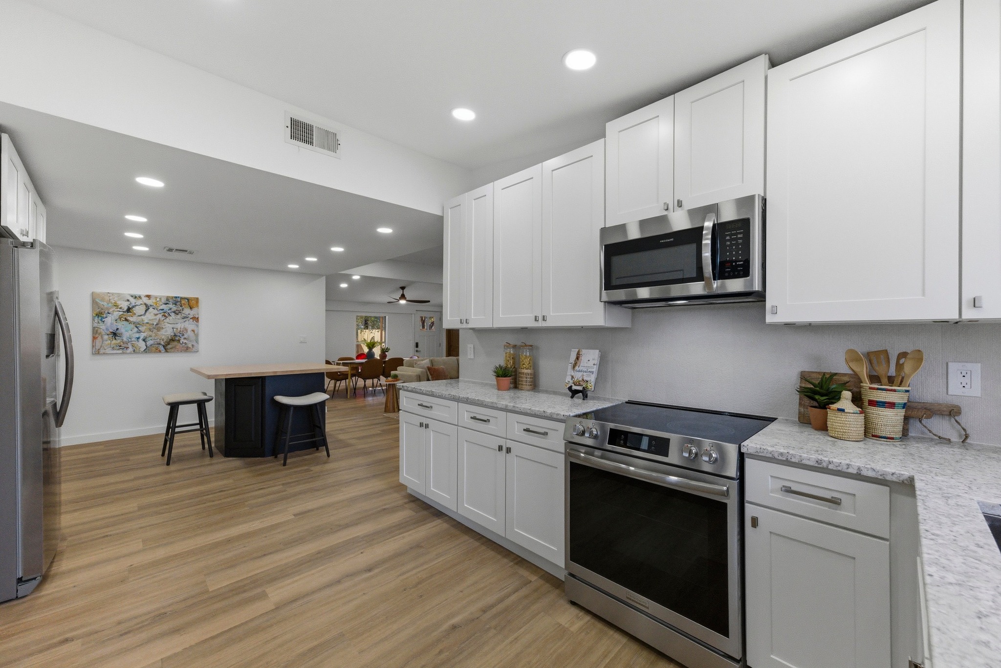 2649 Crazyhorse Pass Austin, TX 78734 - Photo 13 of 40 Two tone kitchen featuring stainless steel appliances, light stone counters, recessed lighting, light wood-type flooring, and ceiling fan