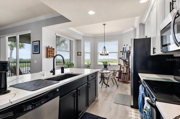 a kitchen with kitchen island granite countertop a stove a sink dishwasher a refrigerator a microwave oven with cabinets and wooden floor