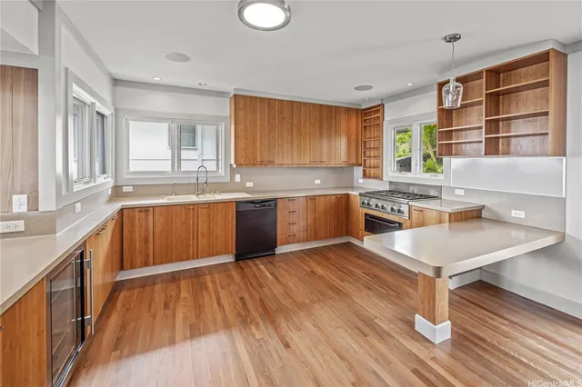a kitchen with stainless steel appliances granite countertop a sink dishwasher a stove and a dining table with wooden floor