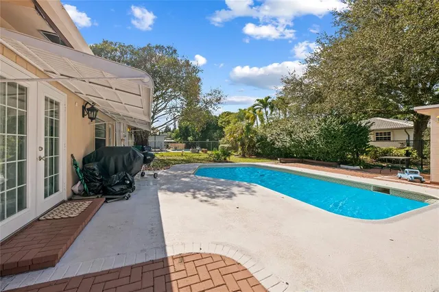 a view of a swimming pool with two chairs in a patio
