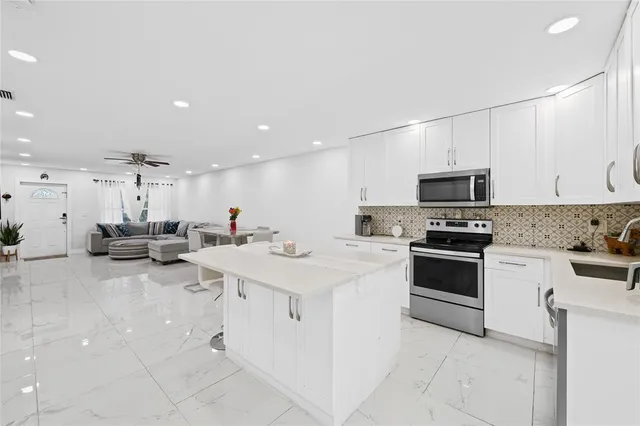 a large white kitchen with white cabinets and stainless steel appliances