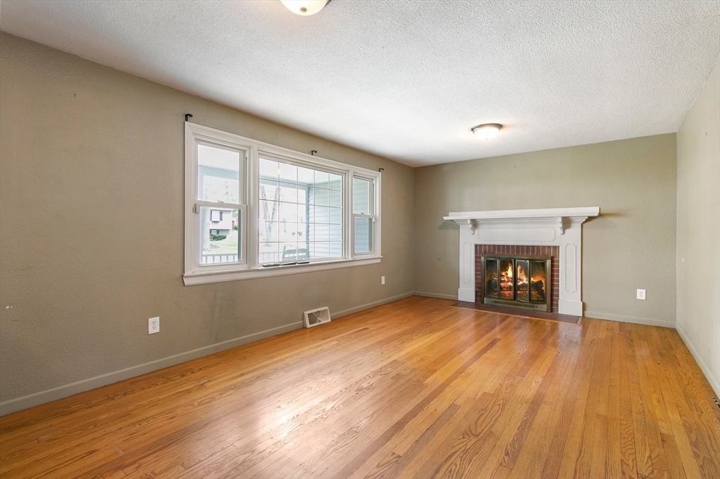 494 Tiffany Street Springfield, MA 01108 - Photo 13 of 40 an empty room with wooden floor fireplace and windows