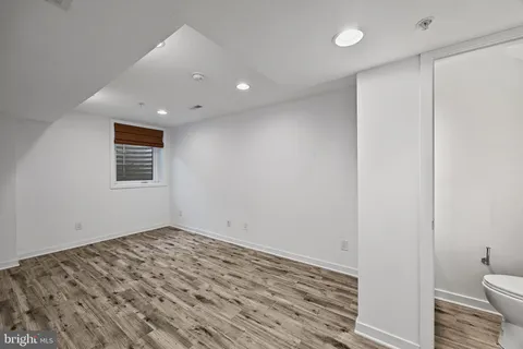 a view of a hallway with wooden floor and a bathroom