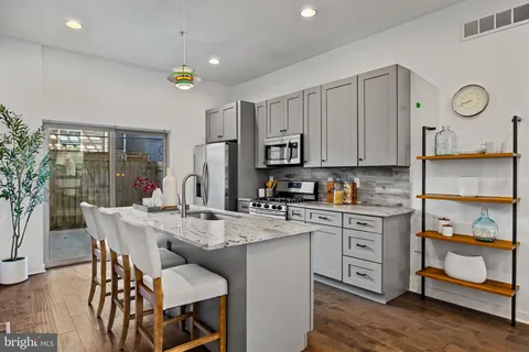 a kitchen with kitchen island granite countertop a table chairs sink and cabinets