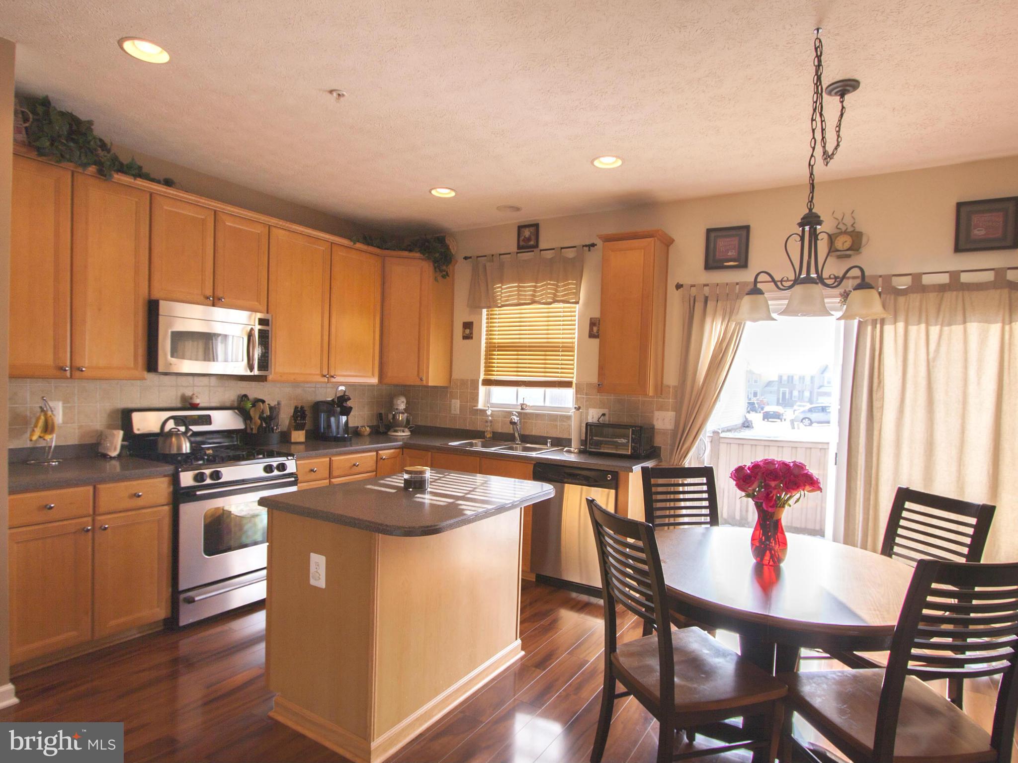 9653 Biggs Road Baltimore, MD 21220 - Photo 3 of 22 a kitchen with a stove a sink dishwasher a dining table and chairs with wooden floor