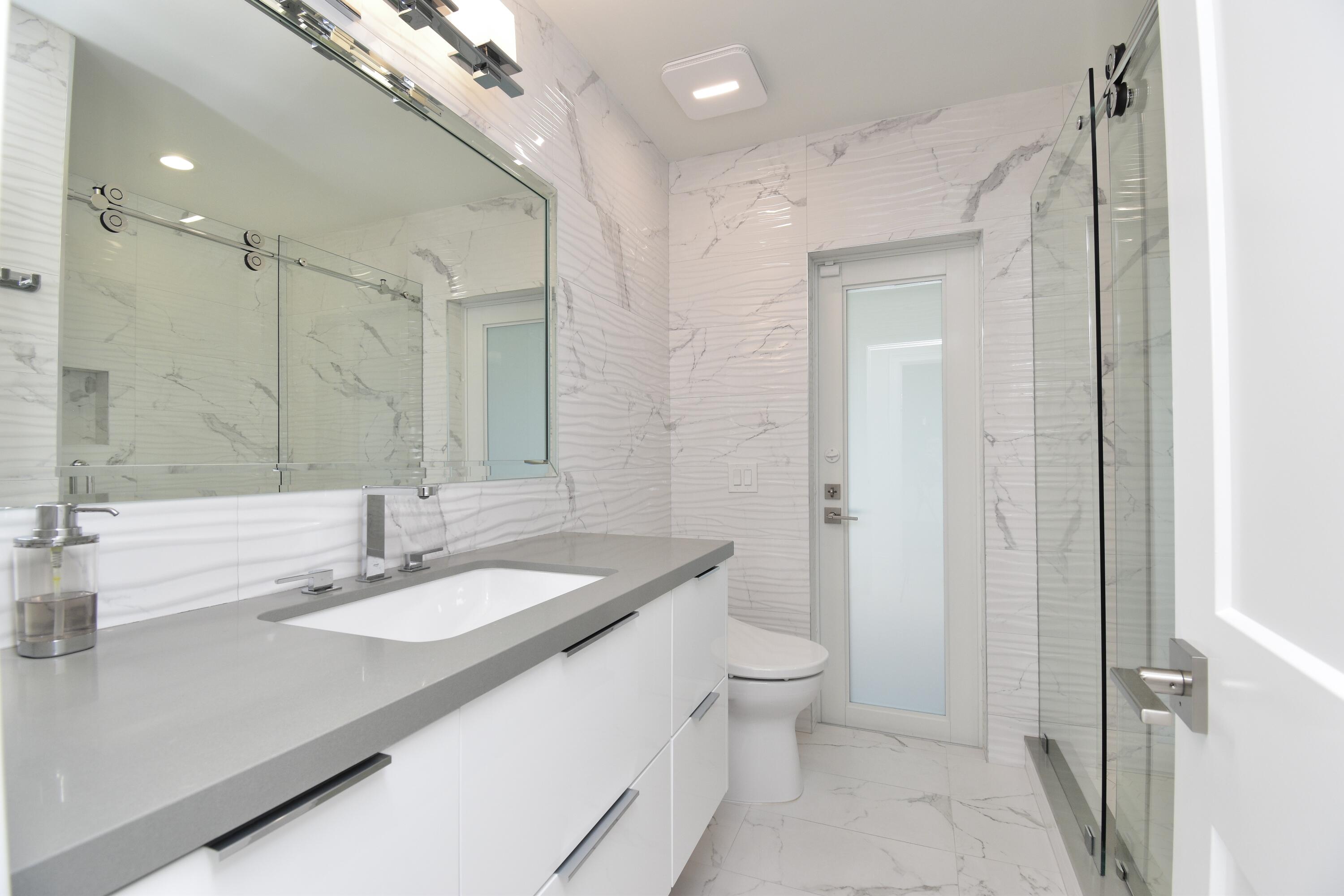20954 Cipres Way Boca Raton, FL 33433 - Photo 47 of 65 a bathroom with a sink a toilet and a large mirror