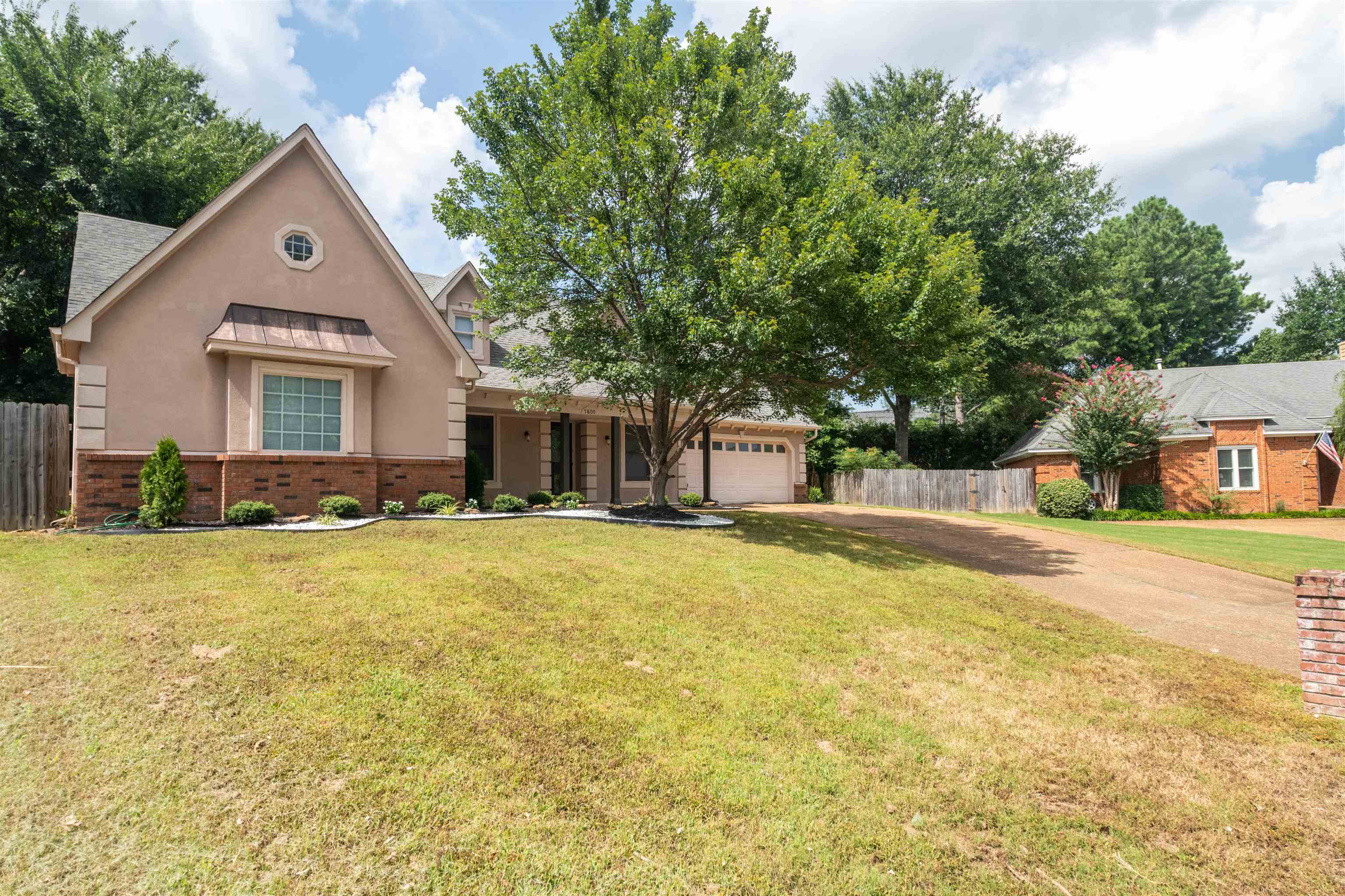 7800 Buck Ridge Cove Memphis, TN 38016 - Photo 5 of 36 Two-story stucco and brick exterior featuring a prominent bay window with copper awning, gabled roofline, and circular accent window