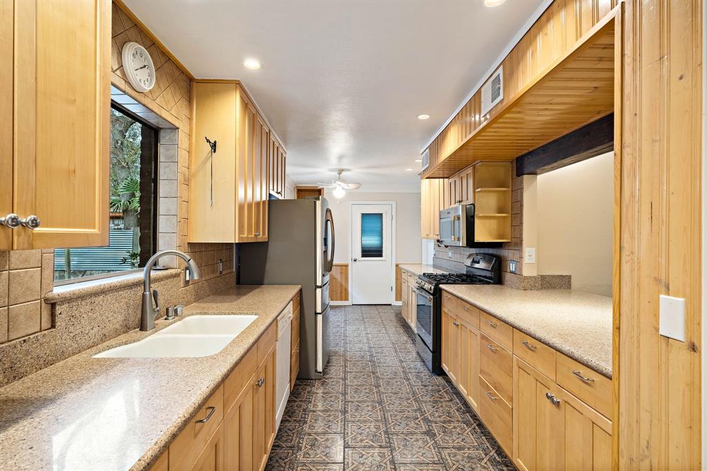 a large kitchen with stainless steel appliances granite countertop a sink a stove and a refrigerator