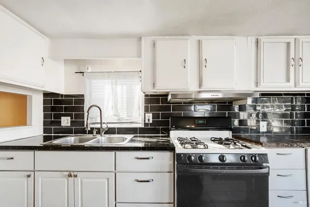 a kitchen with granite countertop a stove sink and cabinets