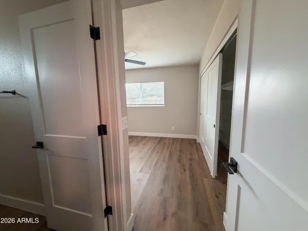 a view of a hallway with wooden floor and a bathroom