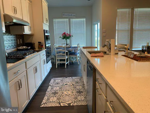 a kitchen with kitchen island granite countertop a sink stove and cabinets