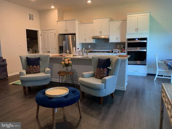 a living room with furniture kitchen view and a wooden floor