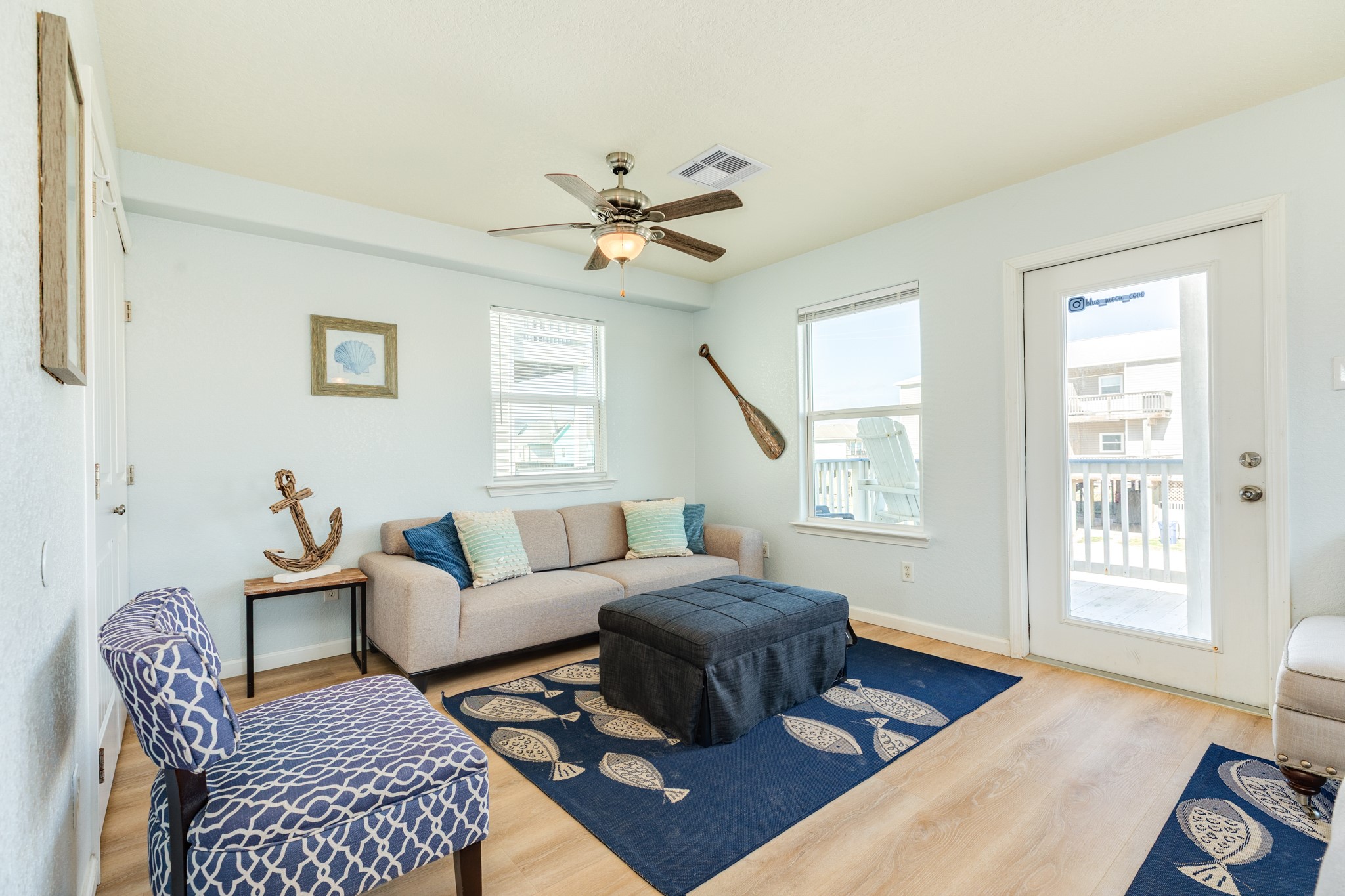 107 Howard Avenue Surfside Beach, TX 77541 - Photo 20 of 38 Comfortable coastal-inspired living space featuring light wood-look flooring, soft neutral tones, and direct balcony access for seamless indoor-outdoor flow.