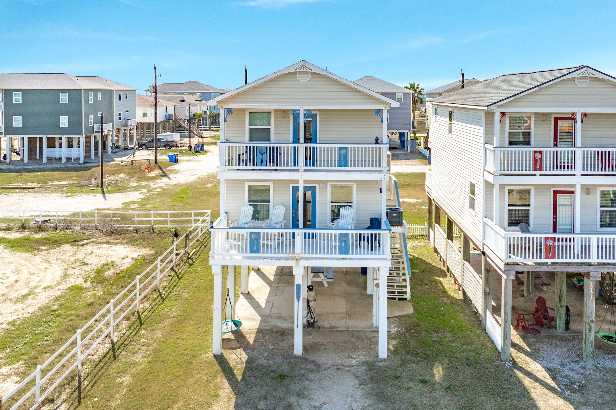 107 Howard Avenue Surfside Beach, TX 77541 - Photo 2 of 38 Elevated coastal home with dual covered balconies, classic siding, and charming blue accents. Raised construction provides covered parking and outdoor space below.