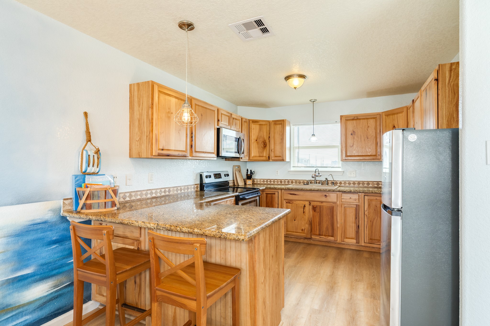 107 Howard Avenue Surfside Beach, TX 77541 - Photo 23 of 38 Functional kitchen with granite countertops, natural wood cabinetry, and a convenient breakfast bar for casual dining.