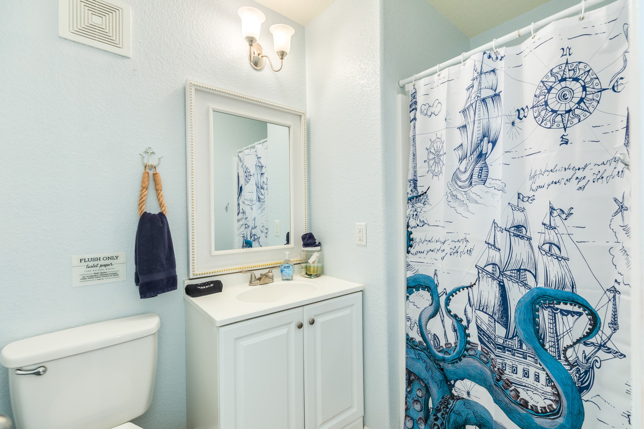 107 Howard Avenue Surfside Beach, TX 77541 - Photo 25 of 38 Bright full bath with vanity storage, updated fixtures, and a nautical-themed shower curtain for a cohesive coastal touch.