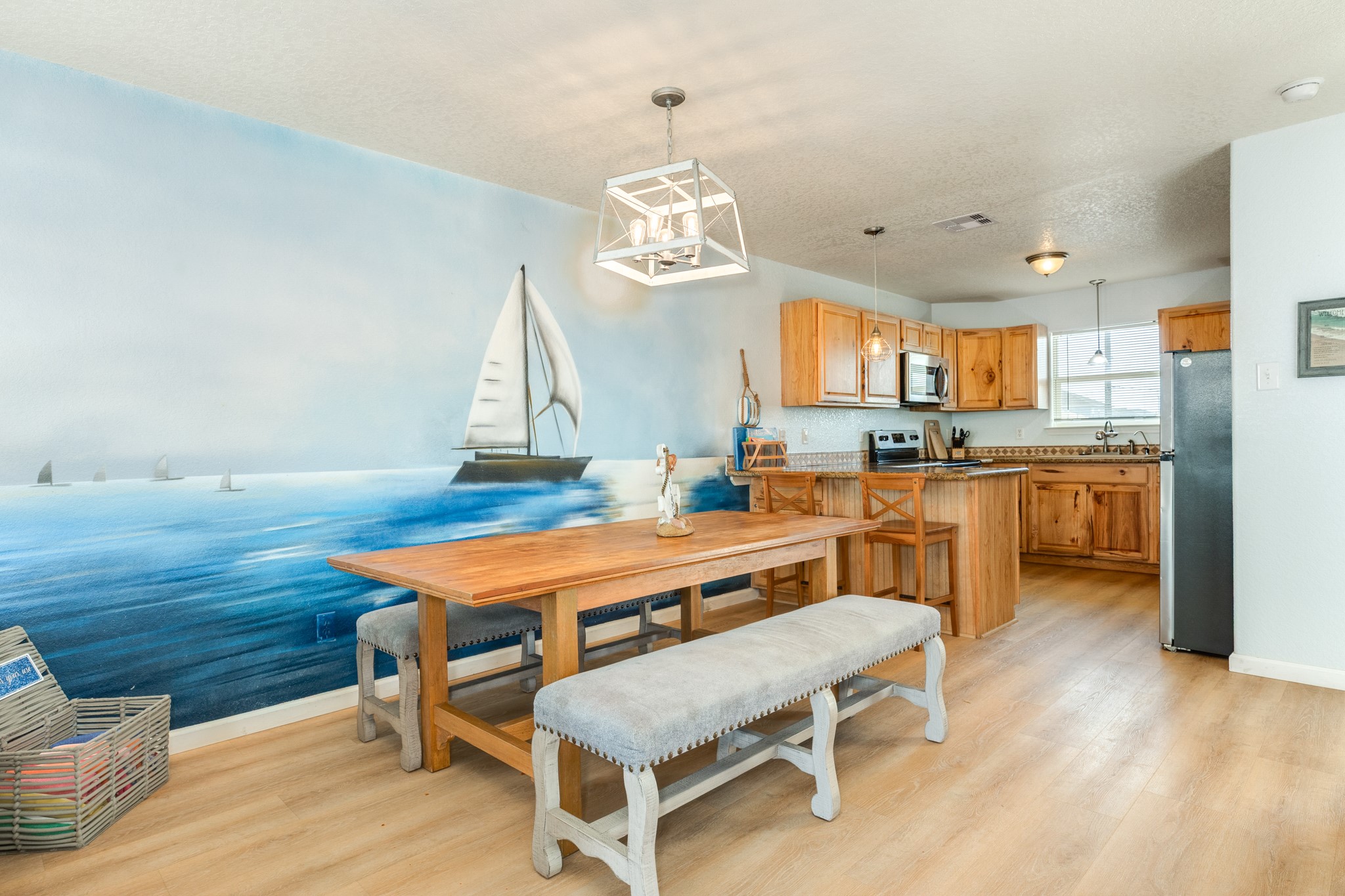 107 Howard Avenue Surfside Beach, TX 77541 - Photo 5 of 38 Dedicated dining space highlighted by a statement light fixture and coastal mural accent wall, offering ample room for shared meals.