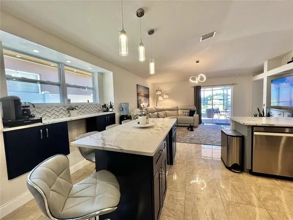 a large kitchen with kitchen island granite countertop a stove a sink a dining table and chairs