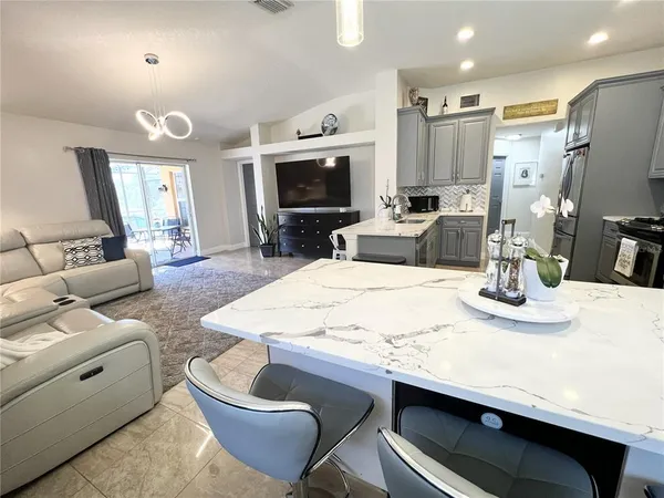 a living room with stainless steel appliances couches a dining table and chairs