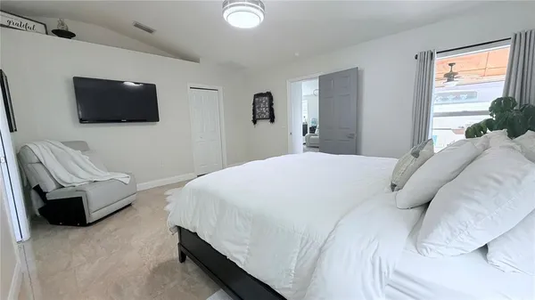 a bedroom with a bed a couch and a flat screen tv