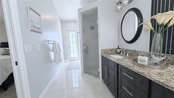 a bathroom with a granite countertop sink a mirror and a shower