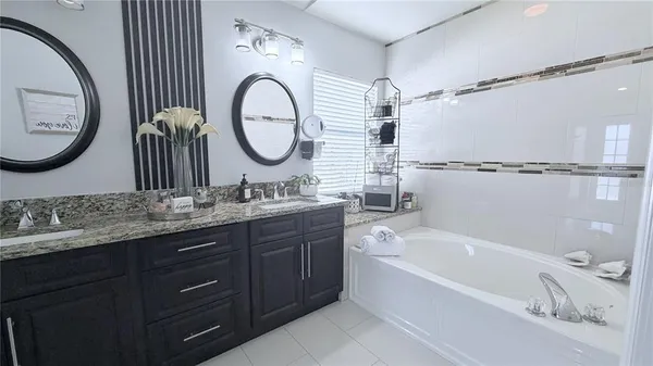 a bathroom with a granite countertop sink mirror vanity and a bathtub