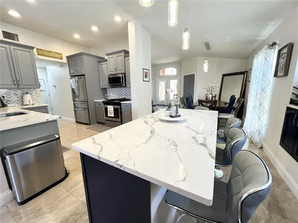 a large kitchen with stainless steel appliances kitchen island granite countertop a sink refrigerator and cabinets