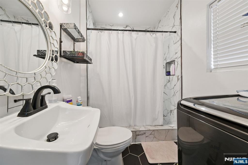 297 West Runyon Street Newark, NJ 07108 - Photo 8 of 14 a bathroom with a sink a toilet and shower curtain