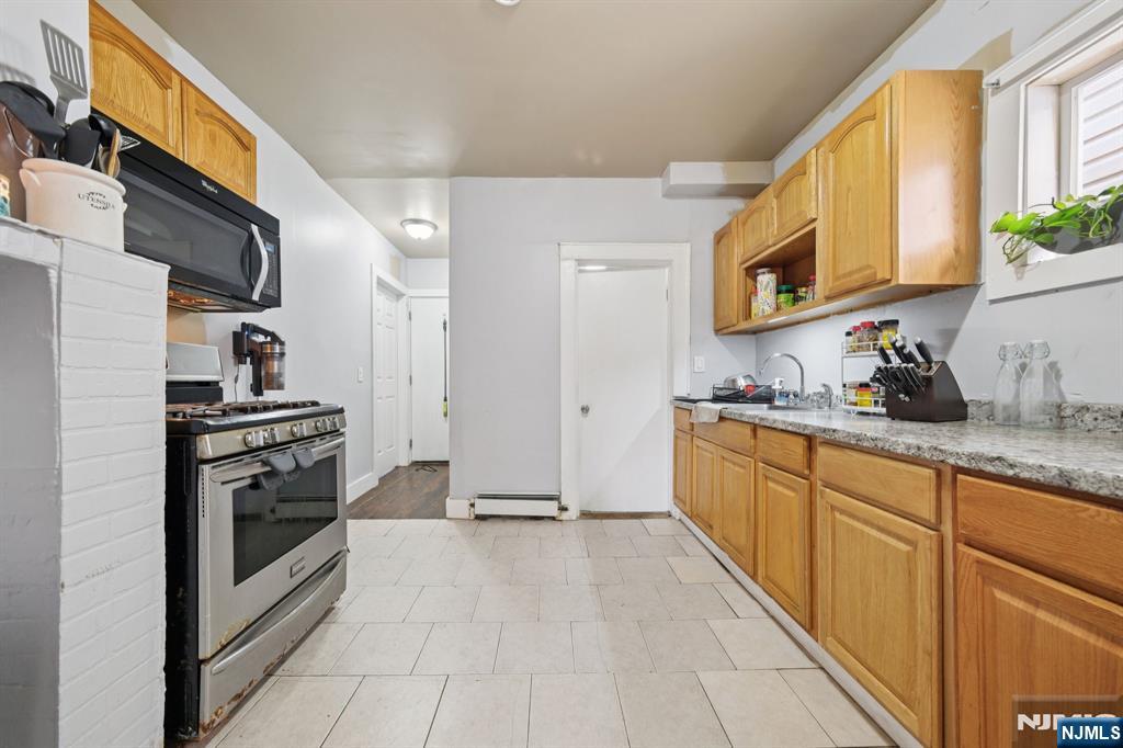 297 West Runyon Street Newark, NJ 07108 - Photo 9 of 14 a kitchen with stainless steel appliances granite countertop a stove a sink and a refrigerator
