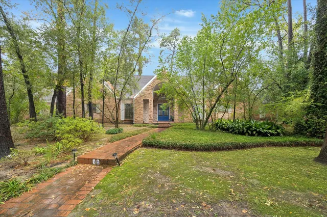 a view of a white house next to a yard and large trees