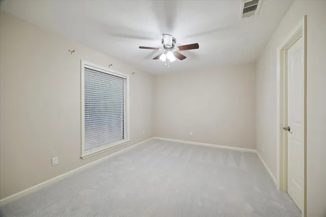 an empty room with closet and a ceiling fan