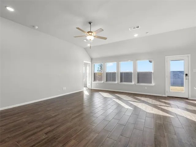 a view of an empty room with a window and wooden floor