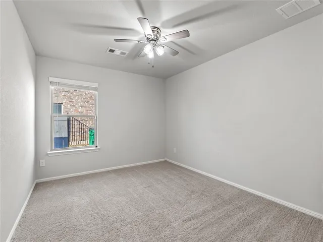 an empty room with windows and chandelier fan