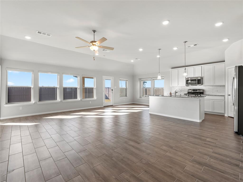 3301 Redbud Flower Trail Venus, TX 76084 - Photo 5 of 28 a view of an empty room with kitchen appliances and a ceiling fan